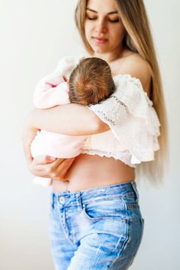 Happy young beautiful mather with smiling baby in her arms. Blurred young mom and baby head in focus.