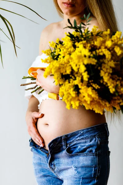 Third month of pregnancy. Close-up of beautiful pregnant girl with flowers. A series of photos of a pregnant girl. Pregnancy, parenthood and expectation concept