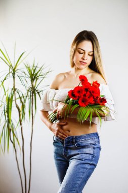 First month of pregnancy. Beautiful pregnant woman with flowers. A series of photos of a pregnant girl. Concept of pregnancy, motherhood, mothers day