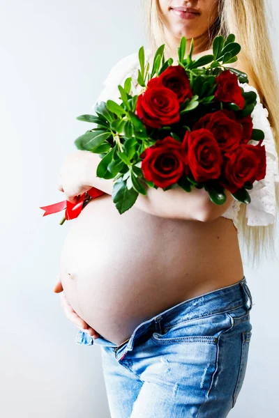 Eighth month of pregnancy. Close-up of beautiful pregnant girl with flowers. A series of photos of a pregnant girl. Pregnancy, parenthood and expectation concept