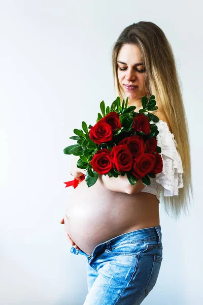 Eighth month of pregnancy. Beautiful pregnant woman with flowers. A series of photos of a pregnant girl. Concept of pregnancy, motherhood, mothers day