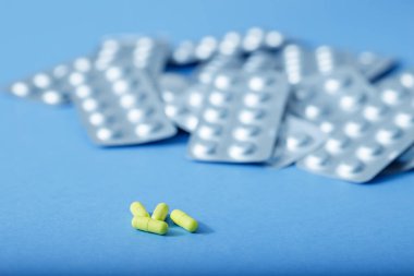 Sarı kapsüller ve farklı haplar. Farklı haplar. Fotokopi alanına sahip açık mavi kağıt arkaplanı tıbbi ve farklı kavramları