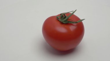 Kırmızı domates beyaz arka planda döner. Video.