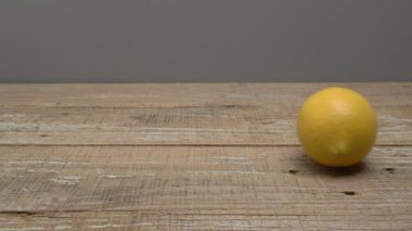 Gri arka planda ahşap bir zeminde duran bir limon rulosu. Video.