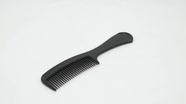 Siyah plastik bir tarak beyaz bir arkaplanda döner. Video.