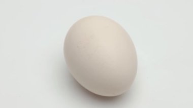 Yakın planda dönen bir tavuk yumurtası. Beyaz arkaplan
