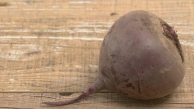 Taze bir pancar, zengin dokusunu ve canlı rengini sergileyerek, kırsal ahşap bir yüzeyde huzur içinde yatar.