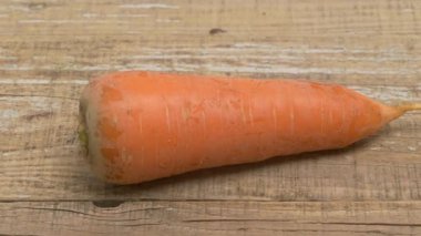 Canlı, parlak turuncu bir havuç güzel bir şekilde kırsal, eski ahşap bir masada dinleniyor, doğal güzelliğini sergiliyor.