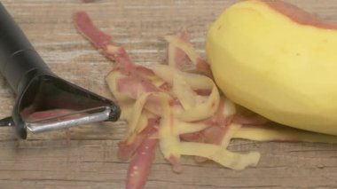 Ahşap bir yüzey üzerinde kabuğu soyulmuş, parlak sarı bir muzun detaylı görüntüsü.