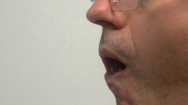 Gözlüklerini, belirgin yüz hatlarını ve ifadesini vurgulayan bir adamın detaylı bir yakın görüntüsü.