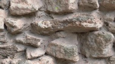 Eşsiz dokularını ve çeşitli toprak tonlarını güzel bir şekilde sergileyen engebeli taştan bir duvarın yakın görüntüsü.