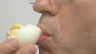 Bir adam kaynamış yumurtadan zevk alıyor, lezzetli dokusunu ve sunduğu eşsiz lezzet deneyimini vurguluyor.