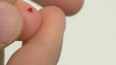 Parmak ucuna dikkatlice tünemiş küçük bir kan damlasının insan biyolojisini gösteren yakın plan, detaylı bir görüntüsü.