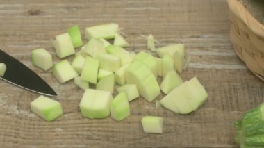 Kırsal bir ahşap yüzeye kesilmiş yeşil sebze parçaları serilir. Hazırlık için keskin bir bıçağın yanında.