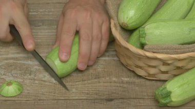 Yetenekli bir şef, yakınlarda bir sepet kabakla, ahşap bir yüzeyde taze kabak dilimler.