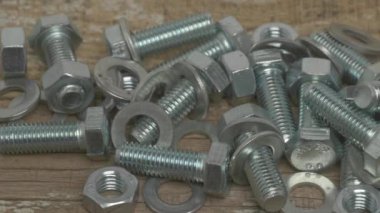 Tahta bir yüzeye yerleştirilmiş cıvata, fındık ve çamaşır gibi çeşitli metal bağlayıcılardan oluşan bir koleksiyon.