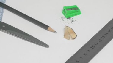 Temiz bir çalışma alanındaki kalem, bileyici ve cetvel de dahil olmak üzere temel sanat malzemeleri koleksiyonu..