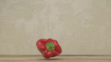Taze, canlı kırmızı bir dolma biber zarif bir şekilde havada asılı, parlak yüzeyi ve parlak rengini sergiliyor.