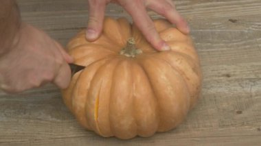 Bir balkabağını ustalıkla oyarken çekilmiş bir fotoğraf. Cadılar Bayramı temalı dekorasyonlar için kesinlikle mükemmel.