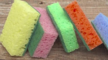 Ahşap bir yüzeye yerleştirilmiş çok renkli temizlik süngerlerinin göz alıcı ve canlı bir görüntüsü.