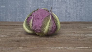 Çarpıcı ve canlı bir mor karnabahar eşsiz ve cesur rengini taşralı ahşap bir arka plana karşı sergiliyor.