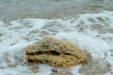 Yumuşak okyanus dalgalarına kısmen batmış bir kayanın yakın çekimi ihtişam ve zarafeti gözler önüne seriyor.