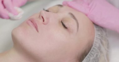 Bir kozmetik uzmanı spa salonundaki genç bir kadına besleyici bir maske takar. Kozmetik kliniğinde tedavi maskesiyle cilt bakımı yapan bir kadının yakın çekimi. Kozmetik ve kaplıca.