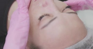 Bir kozmetik uzmanı spa salonundaki genç bir kadına besleyici bir maske takar. Kozmetik kliniğinde tedavi maskesiyle cilt bakımı yapan bir kadının yakın çekimi. Kozmetik ve kaplıca.