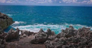 Büyük dalgaların yavaş hareketi kıyı şeridindeki kayalara çarpıyor. Bali 'nin Nusa Dua adasında su baskını. Hint Okyanusu 'nun güzel ve güçlü dalgaları kayalara çarpıyor..