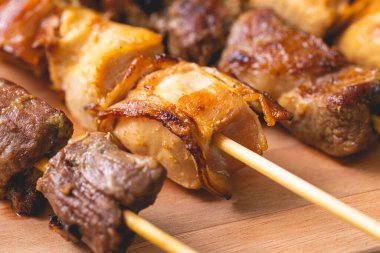 Brazilian churrasquinho. Kebabs with beef and chicken meat and bacon, known in Brazil by the name of churrasquinho. Wooden board, farofa and vinaigrette in the composition. Above view.