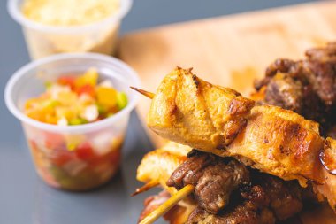 Brazilian churrasquinho. Kebabs with beef and chicken meat and bacon, known in Brazil by the name of churrasquinho. Wooden board, farofa and vinaigrette in the composition. Above view.