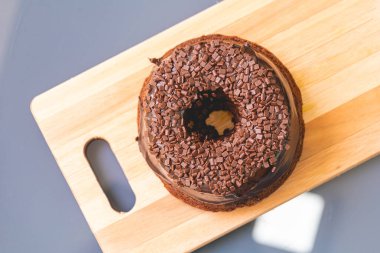 Chocolate cake with creamy chocolate sauce and decorated with chocolate sprinkles on a wooden board.