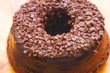 Chocolate cake with creamy chocolate sauce and decorated with chocolate sprinkles on a wooden board.