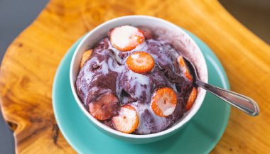 Acai with strawberry and condensed milk in a bowl. Brazilian food, dessert.