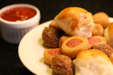 Makro shot 'lı ketçaplı sos tutacağı olan bir tabakta çeşitli Brezilya çerezleri. Siyah arkaplan.