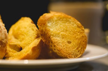 Beyaz çay tabağında margarinli kızarmış ekmek, yakın plan. 