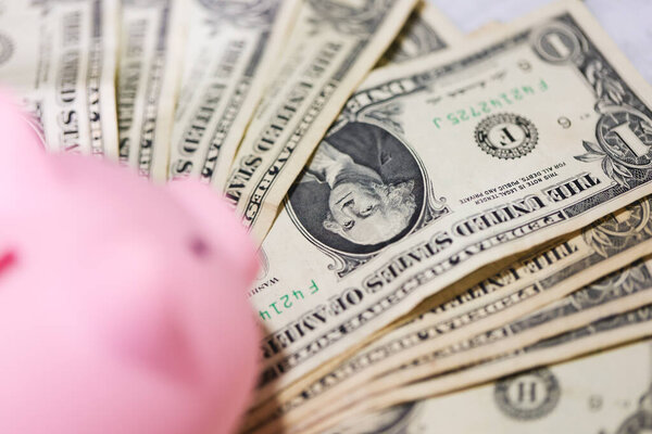 Закрыть денежный фон банкнотами по доллару и копилкой. Концепция экономики и финансов. 