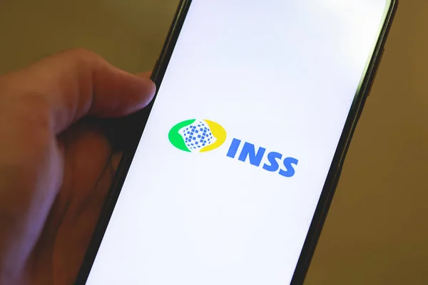 stock image Brasilia, Federal District, Brazil - April, 2023. Cell phone with the INSS logo on the screen. National Institute of Social Security in Brazilian Portuguese. 