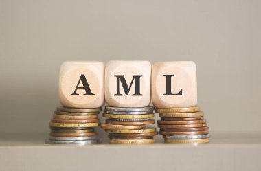 AML kısaltması tahta küplere ve gri arka planda bozuk paralara yazılmış. Stüdyo fotoğrafı.  