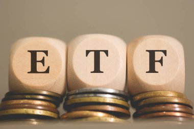 Tahta küplere ETF kısaltması ve gri arka planda bozuk paralar. Stüdyo fotoğrafı.  
