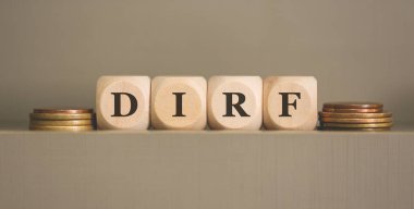 DIRF kısaltması tahta küplere ve gri arka planda bozuk paralara yazılmış. Stüdyo fotoğrafı.  