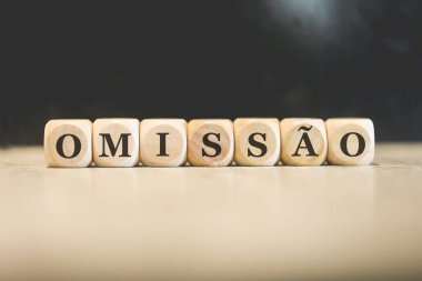 Portekizce OMITTED kelimesi tahtadan küplere yazılmış. Siyah arkaplan. 