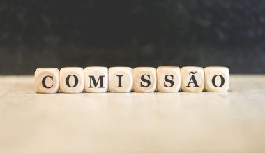 Brezilya Portekizcesinde tahtadan küplere yazılmış COMISSION yazıları. Siyah arkaplan. 
