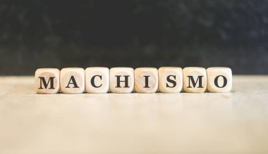 Brezilya Portekizcesinde tahtadan küplere yazılmış MACHISM kelimesi. Siyah arkaplan. 