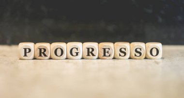 Brezilya Portekizcesi kelime PROGRESS tahtadan küplere yazılmış. Stüdyo fotoğrafı.   