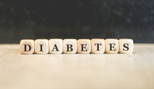 Слово DIABETES написано на деревянных кубиках. Чёрный фон. 