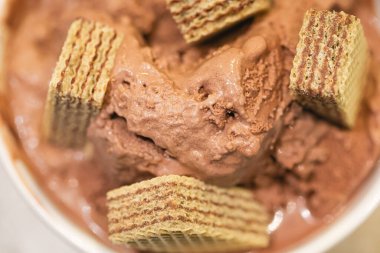 Beyaz kasede çikolatalı dondurma ve kompozisyonda çikolatalı gofret. Yakın plan fotoğraf..