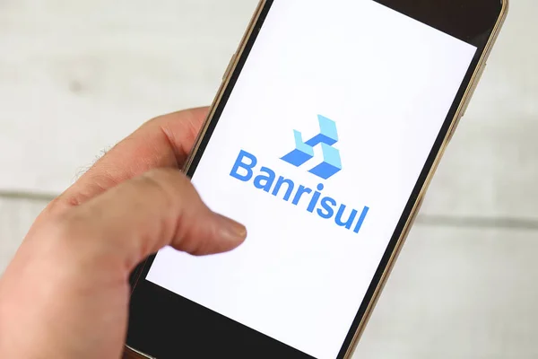 stock image Brasilia, Federal District, Brazil - March, 14, 2023: The Banrisul bank logo on the screen of a cell phone