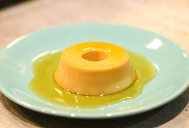 Yeşil bir tatlı tabağında servis edilen küçük bir muhallebi. Portekizce 'de Pudim de leite kondensado denilen Brezilya tatlısı.. 