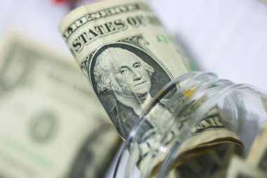 Makro fotoğrafçılıkta cam kavanozlu ahşap bir masanın üzerinde Amerikan Doları banknotları. Para tasarruf kavramı.